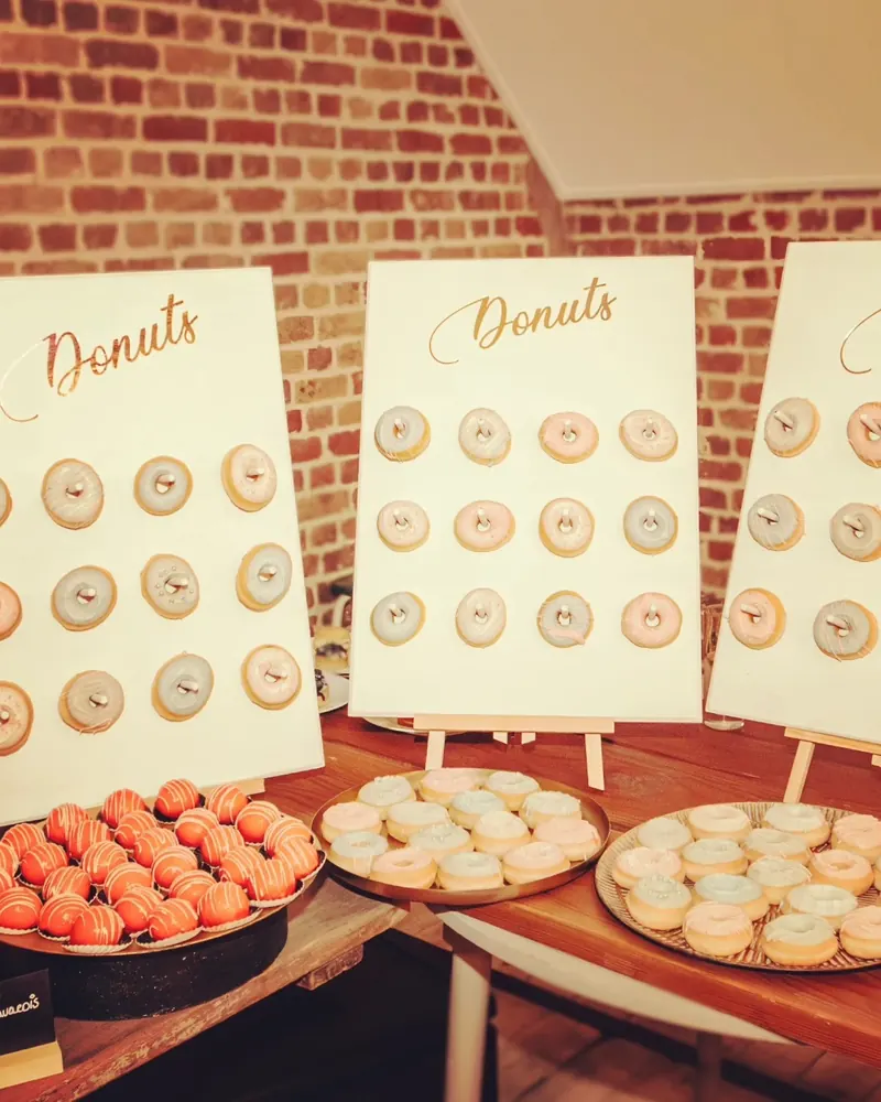 Drie donutwanden met daarvoor schalen macarons en soesjes