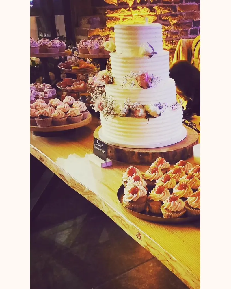 Dessertbuffet met een witte etagetaart met rozen en tientallen cupcakes