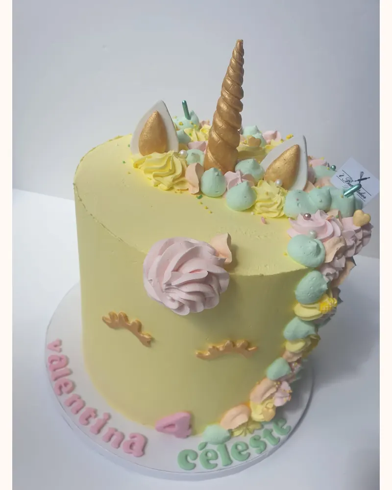 Gele eenhoorntaart met gouden hoorn en pastel toefjes