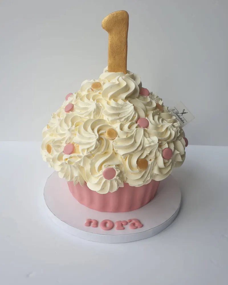 Reuzecupcake-taart met vanillerozetten en een gouden cijfer 1