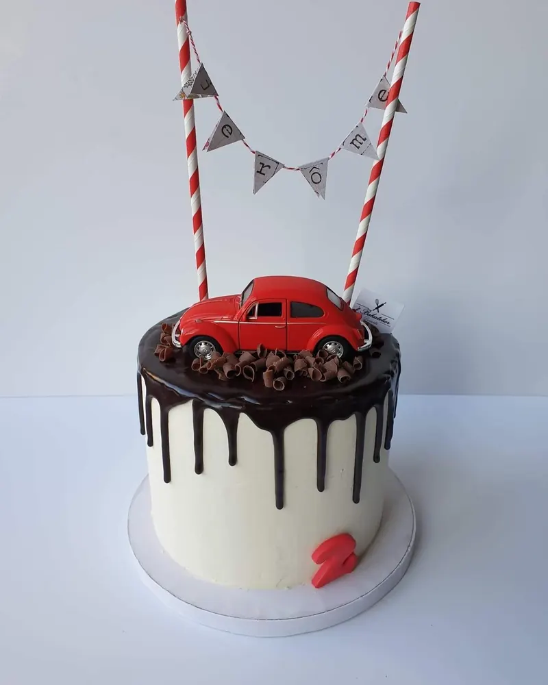 Drip cake met rode speelgoedauto en vlaggetjes