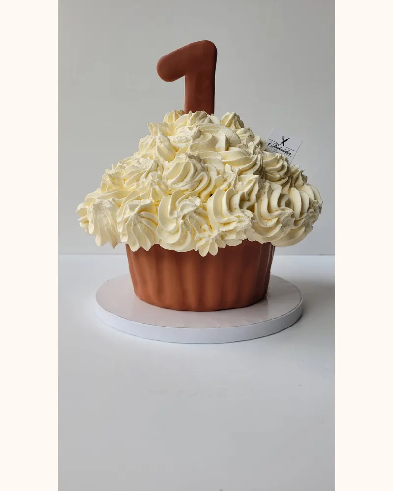 Reuzecupcake-taart met een bruine voet, vanillerozetten en een chocolade cijfer 1